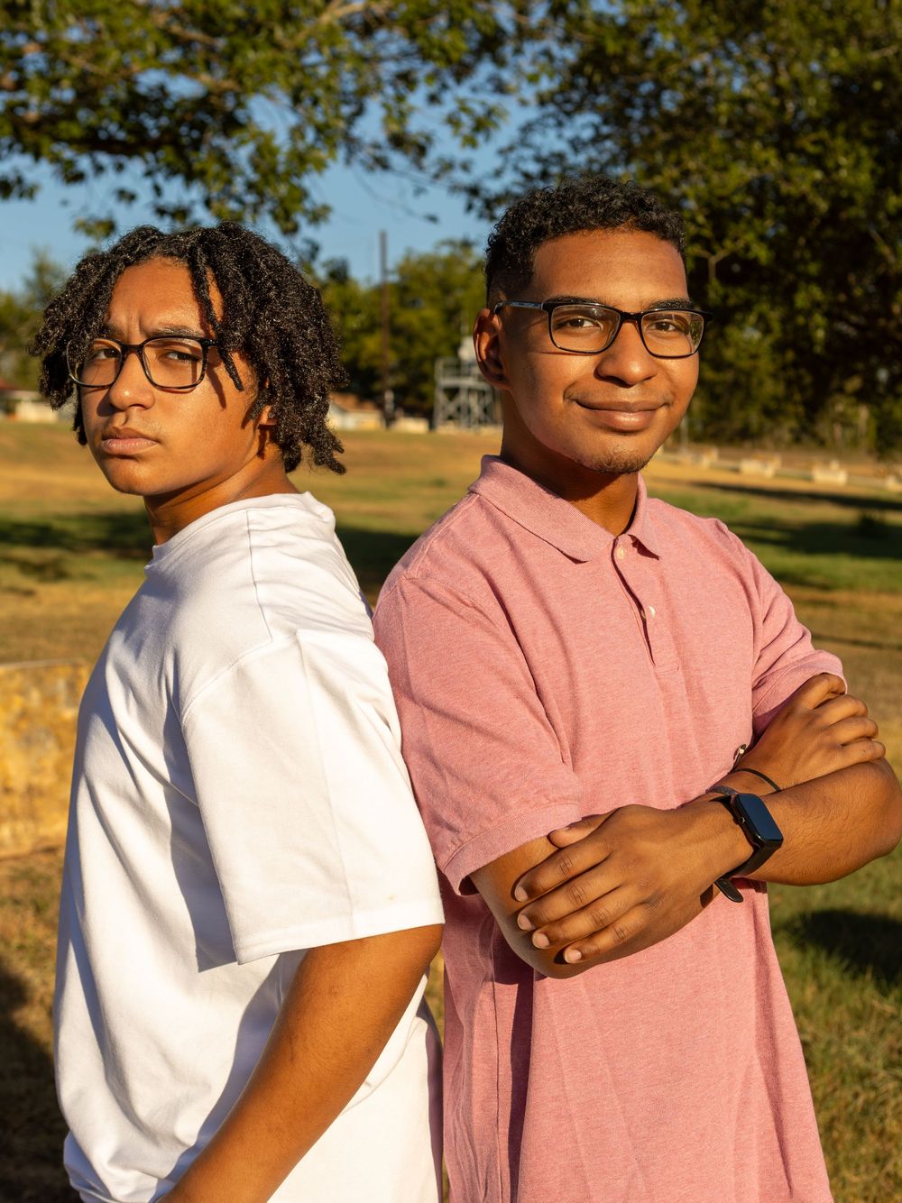 Brothers standing back to back outdoors at Webberville Park.