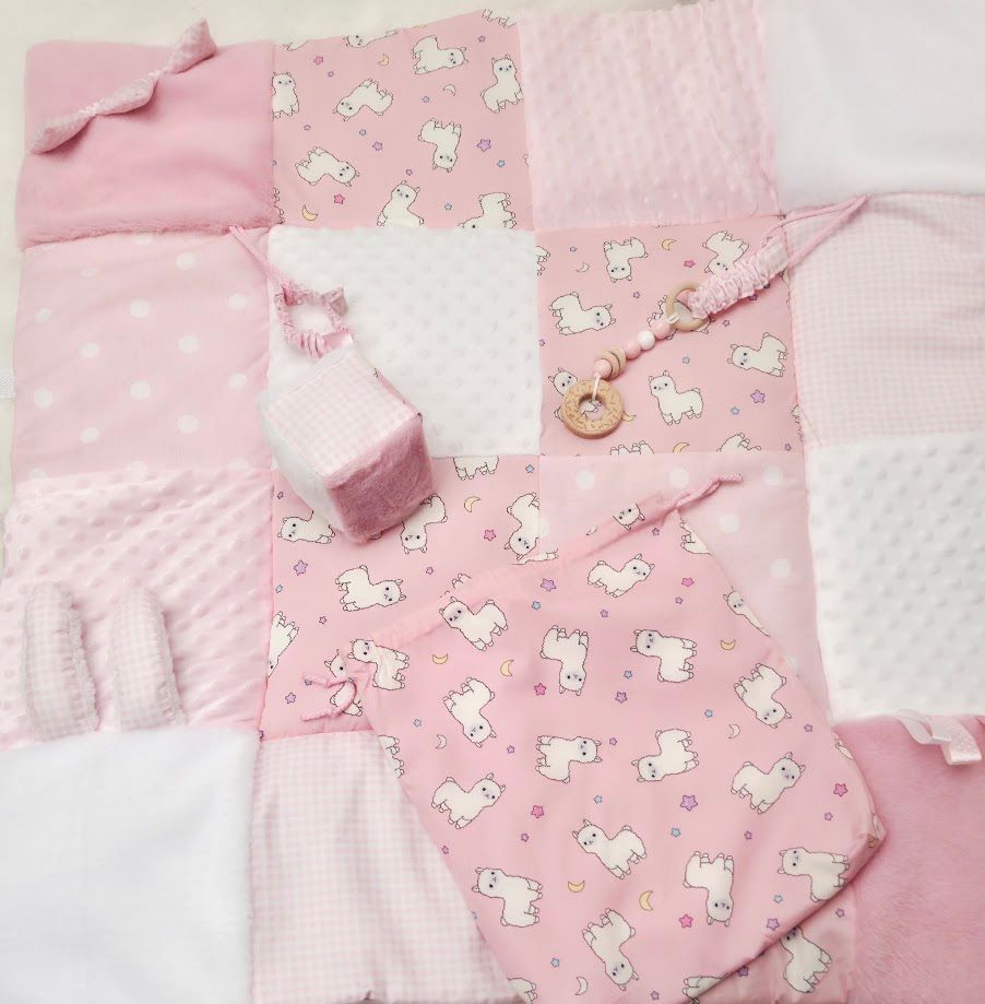 Pink patchwork baby quilt featuring unicorn print fabric squares with minky texture and wooden button accent.