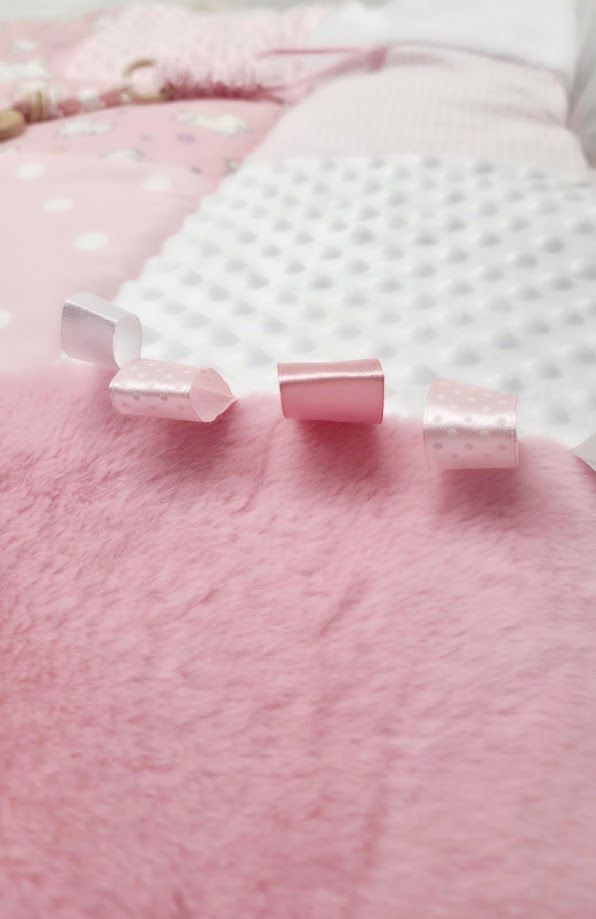 Three small pink and clear plastic caps on a soft pink fluffy surface with a polka dot pillow in the background.