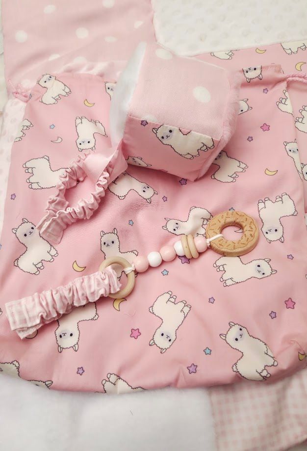 Pink llama print baby gift set with blanket, teether, hair tie, and accessories on white background.