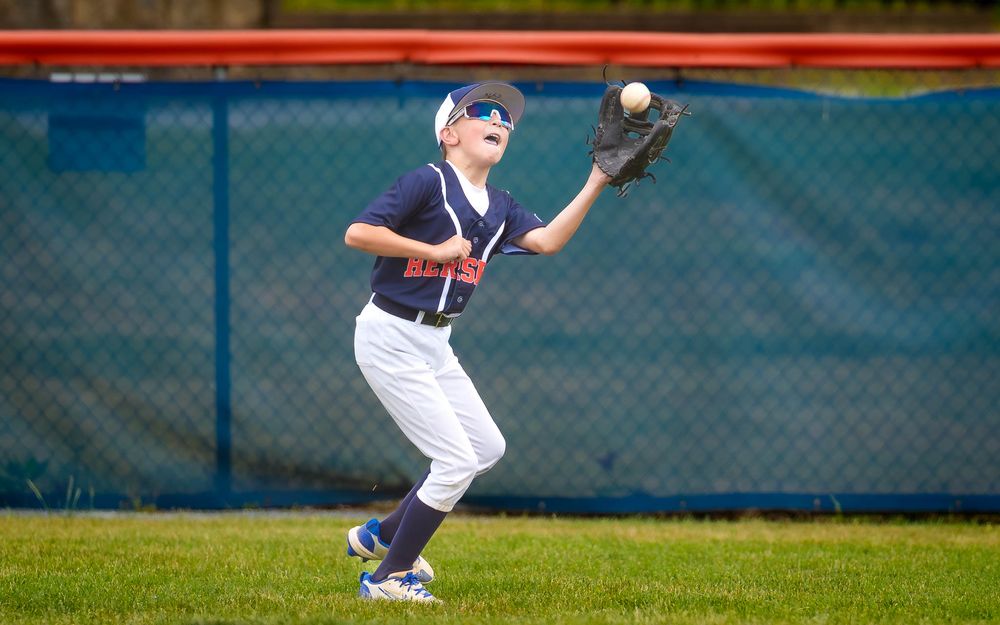 Hershey outfielder tracks a fly ball into his glove in Summer Slam baseball, by Deanna Fox, SportsFox Photography based in Hershey PA