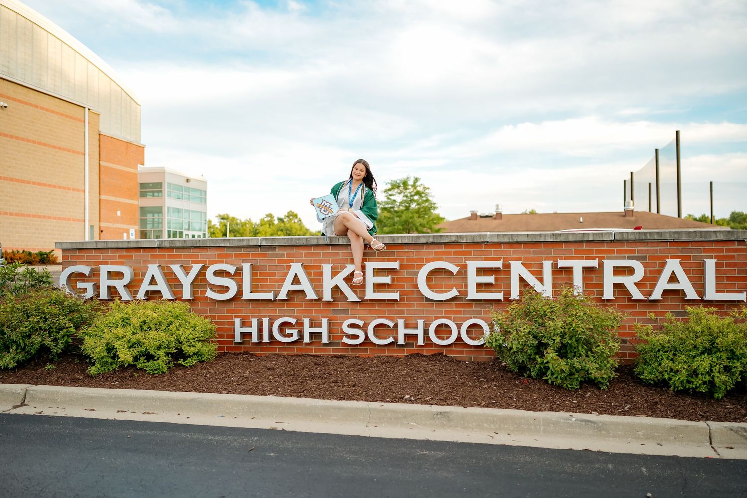 Student poses on Grayslake Central High School sign outdoors on a cloudy day.