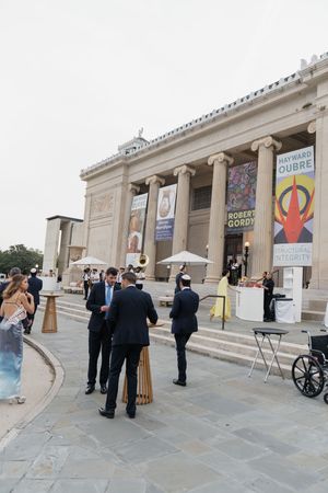 Elegant wedding cocktail hour outside a neoclassical museum with guests mingling on the steps.
