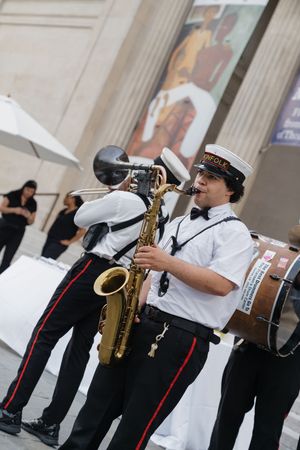 Jazz band musicians in uniform perform outdoors with saxophone and brass instruments at a wedding celebration.