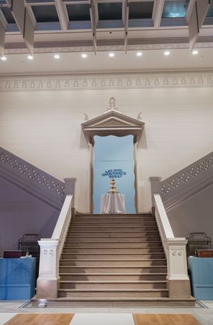 Grand interior staircase with ornate white molding leads to an elegant doorway with decorative pediment in a classical building.