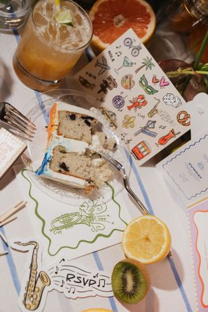 Wedding RSVP stationery with saxophone illustration displayed alongside cake slice and tropical fruit.
