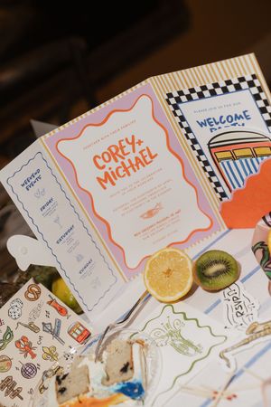 Colorful wedding invitation suite for Corey and Michael displayed with fresh fruit and stickers.