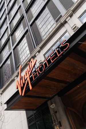 Virgin Hotels illuminated sign on modern building exterior facade in urban city setting.