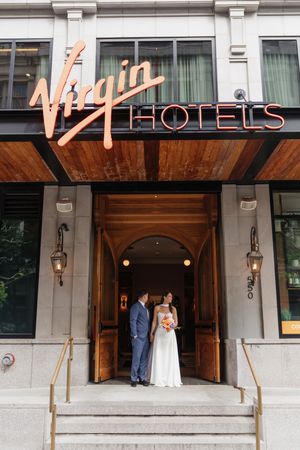 Bride and groom sharing a romantic moment under the Virgin Hotels sign at the entrance steps.
