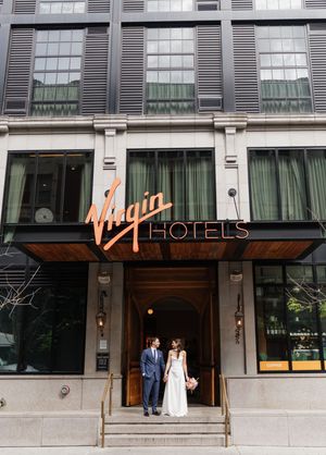 Bride and groom pose at entrance of Virgin Hotels on wedding day.