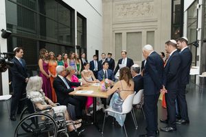 Wedding guests gathering around signing table during elegant reception in grand museum venue.