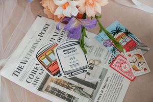 Wedding stationery flat lay featuring The Wedding Post newspaper, brunch invite, and colorful illustrated cards with flowers.