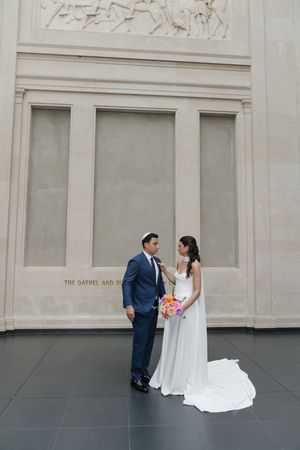 Bride and groom share an intimate moment inside an elegant museum venue on their wedding day.