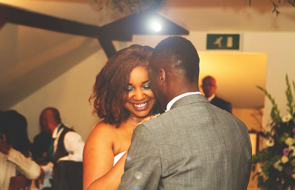 Couple sharing a joyful first dance at a wedding reception, bride smiling broadly in elegant attire. At Oaks farm wedding venue in Surrey