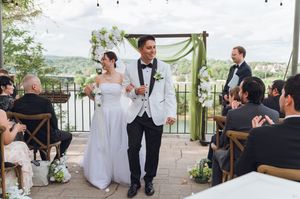 Happy newlyweds walk down the aisle at an elegant outdoor wedding ceremony on a scenic terrace.