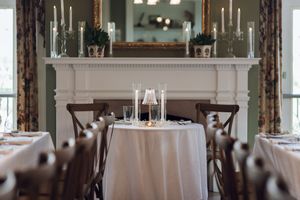 Elegant wedding reception venue with fireplace, candles, and white tablecloths.