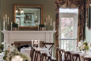 Elegant wedding reception room with fireplace, candelabras, white tablecloths, and floral centerpieces.