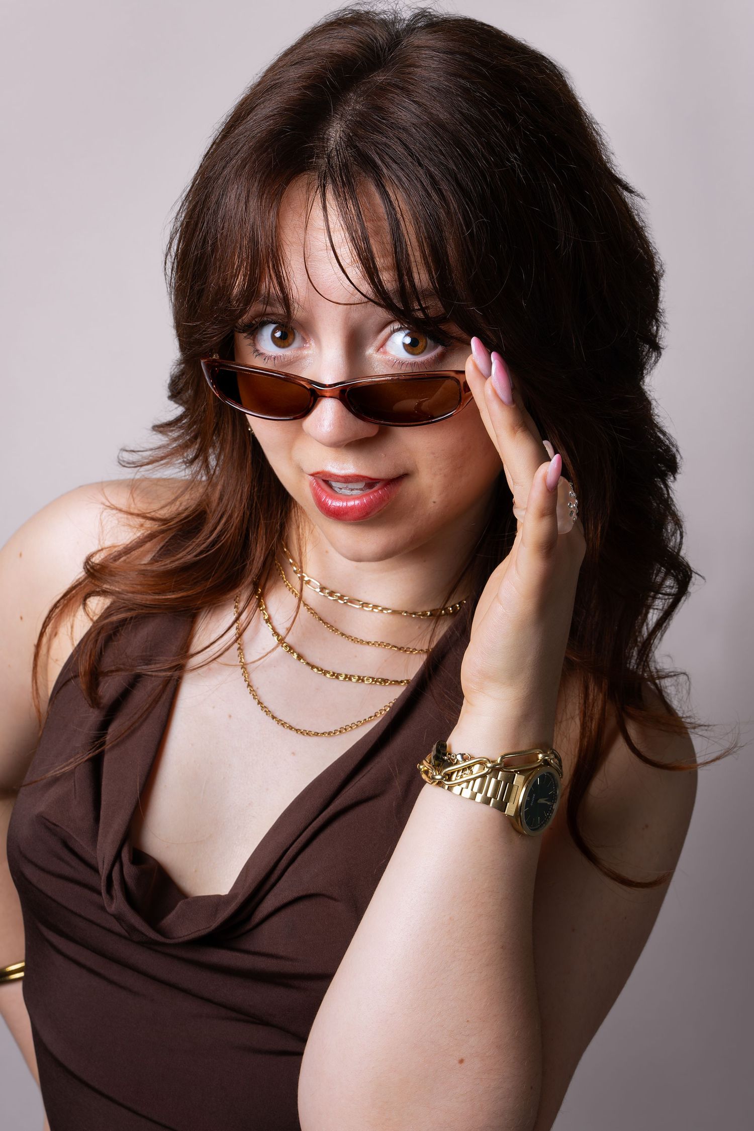 Portrait studio d'une femme ajustant ses lunettes teintées devant l'objectif.