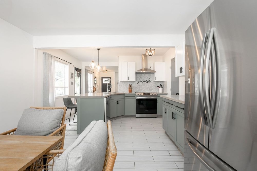 Open kitchen with gray cabinets, stainless steel appliances, white tile floors, and casual dining seating area.