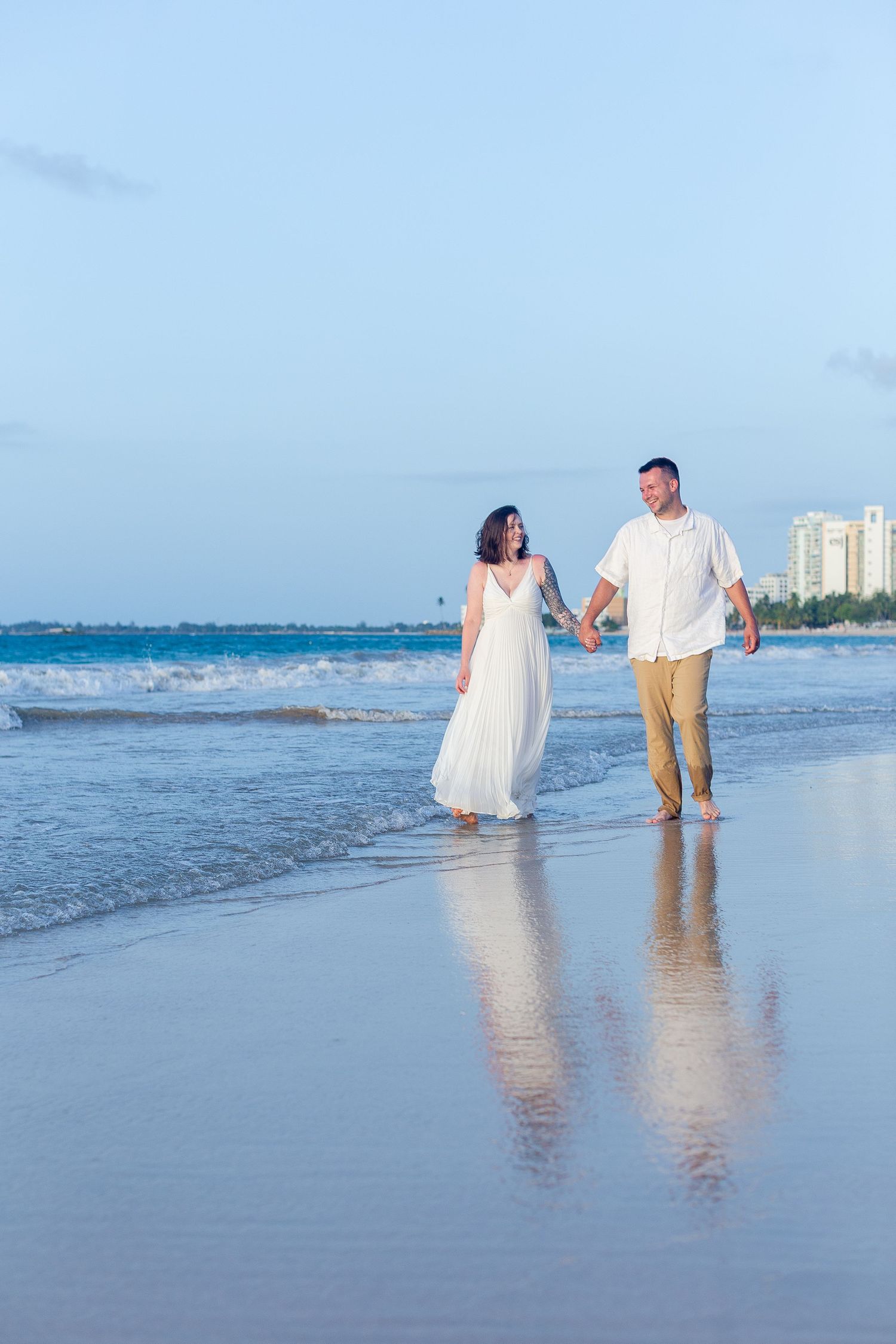 Couples portrait on the beach in Isla Verde, Carolina, Puerto Rico. The couple and their reflection in the wet sand.