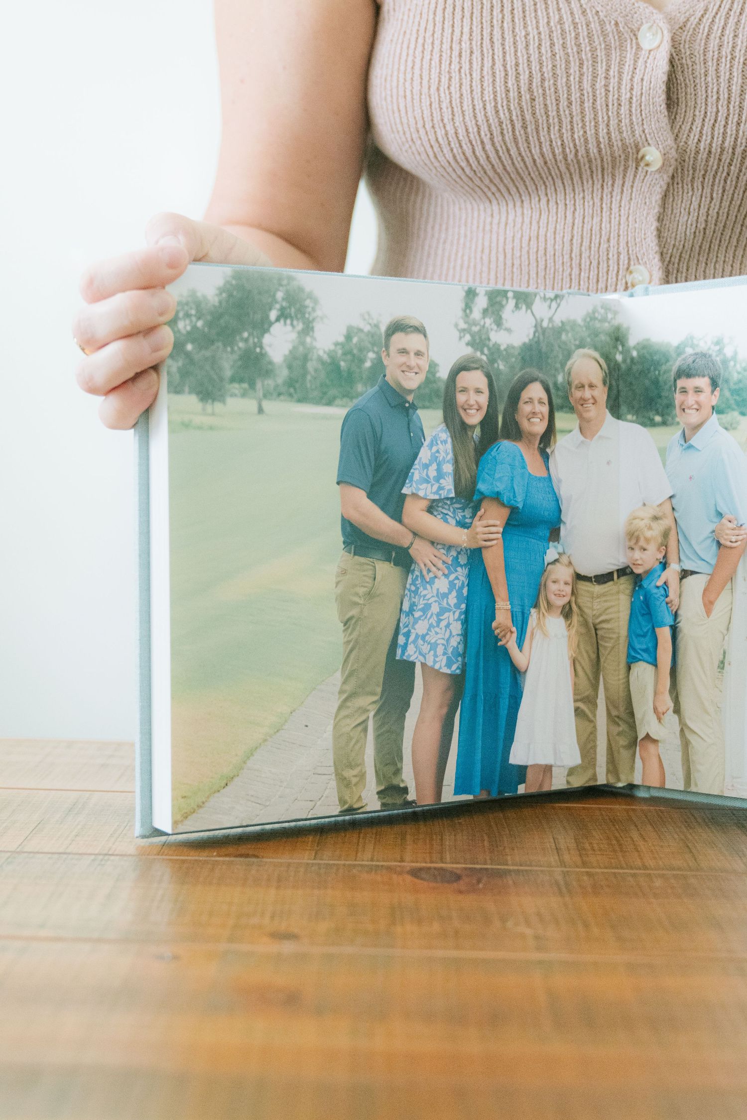 Family photographer presenting a handcrafted heirloom album from the Templeton family's St. Simons Island portrait session.