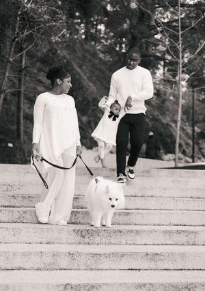 Black and white photo of a family with a white Samoyed dog walking down outdoor stone steps in a park.
