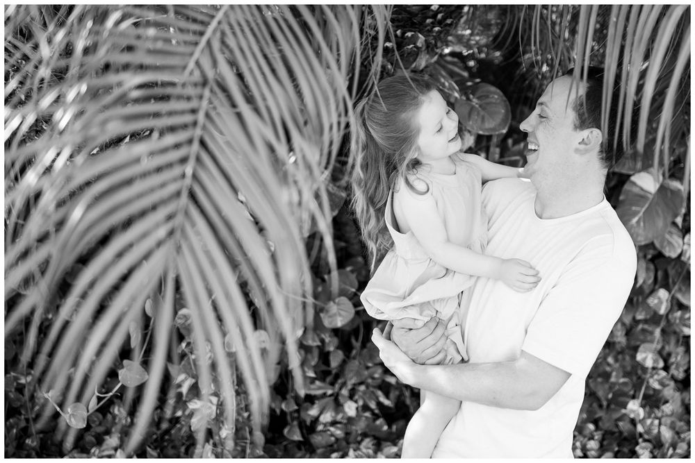Grand Velas Riviera Nayarit Family Photographer capturing a father holding his daughter among tropical palms during candid family photos.