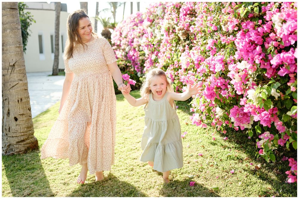 Grand Velas Riviera Nayarit Family Photographer capturing a mother and daughter by blooming bougainvillea during family photos.