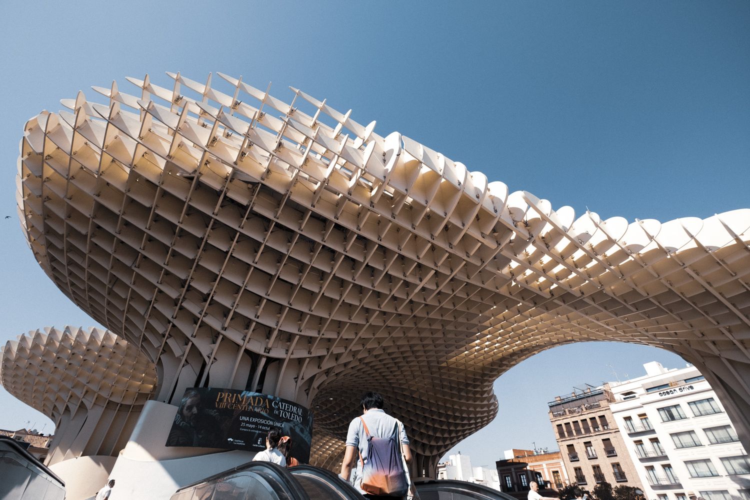 Metropol Parasol wooden lattice structure in Seville, Spain, with people walking beneath its unique mushroom-shaped canopy.
