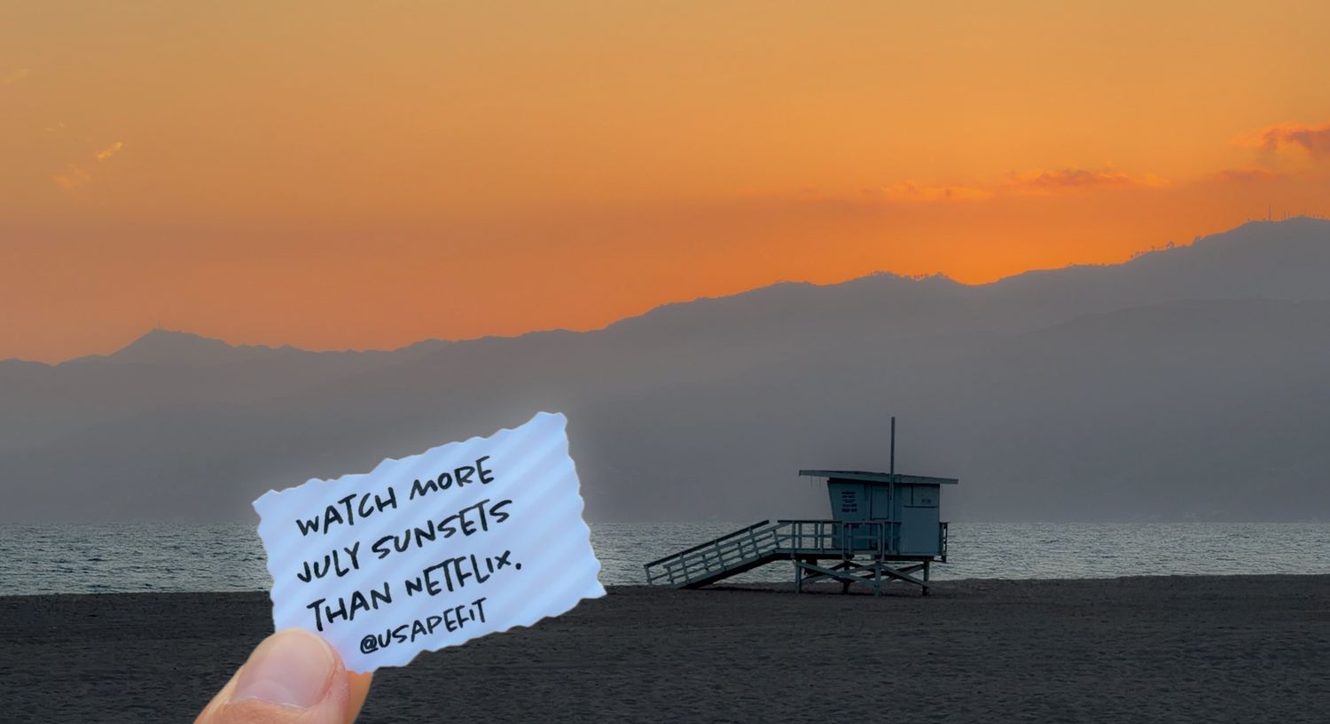 Hand holding a note saying watch more sunsets than Netflix at Santa Monica Beach during a golden orange sunset.