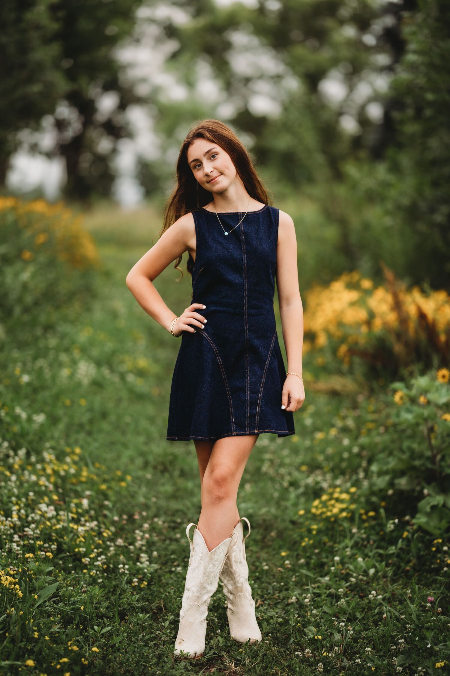 Young woman in a light yellow strapless dress smiling on a country path at golden hour sunset.