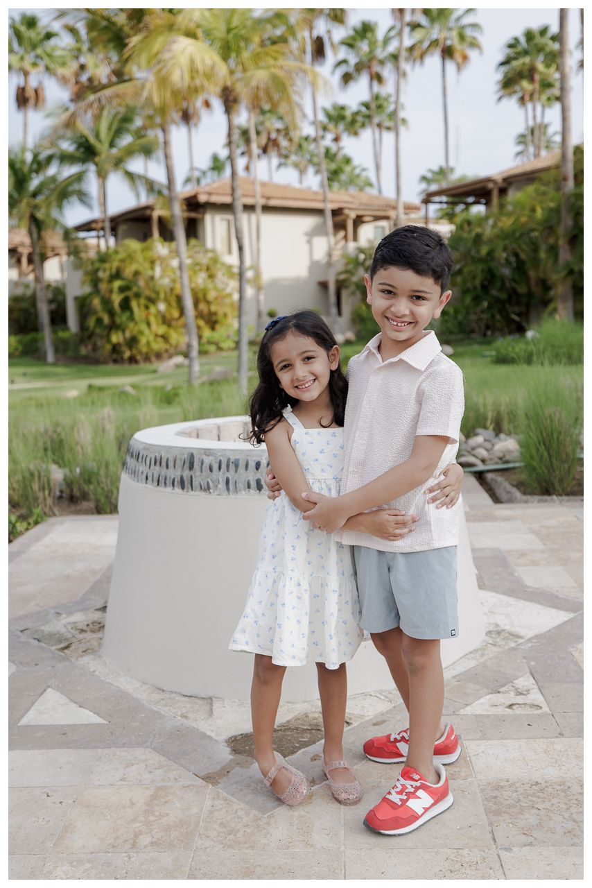 St Regis Punta Mita Family Photographer capturing siblings hugging near a tropical fountain during Punta Mita Family Photos.