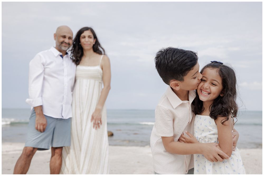 St Regis Punta Mita Family Photographer capturing siblings sharing a beach hug with parents nearby during Beach Family Photo Session.