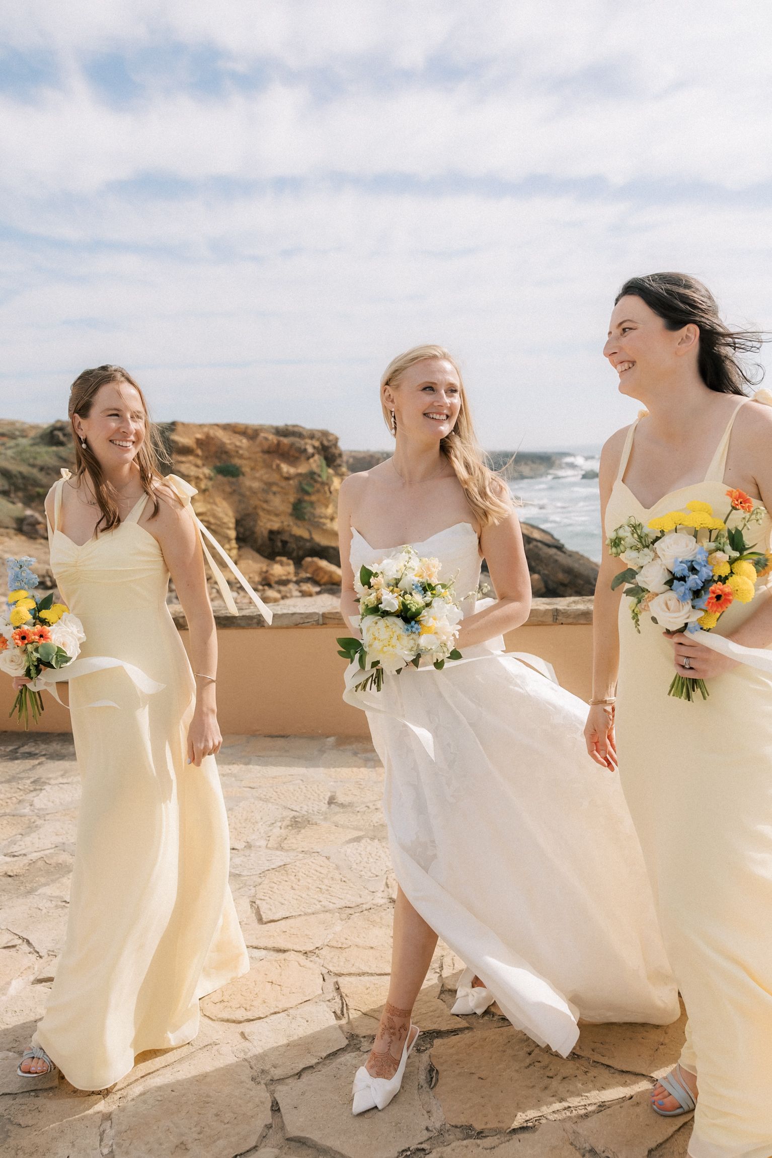 Bride sharing joyful moments with her bridesmaids after an oceanfront destination wedding in Portugal.