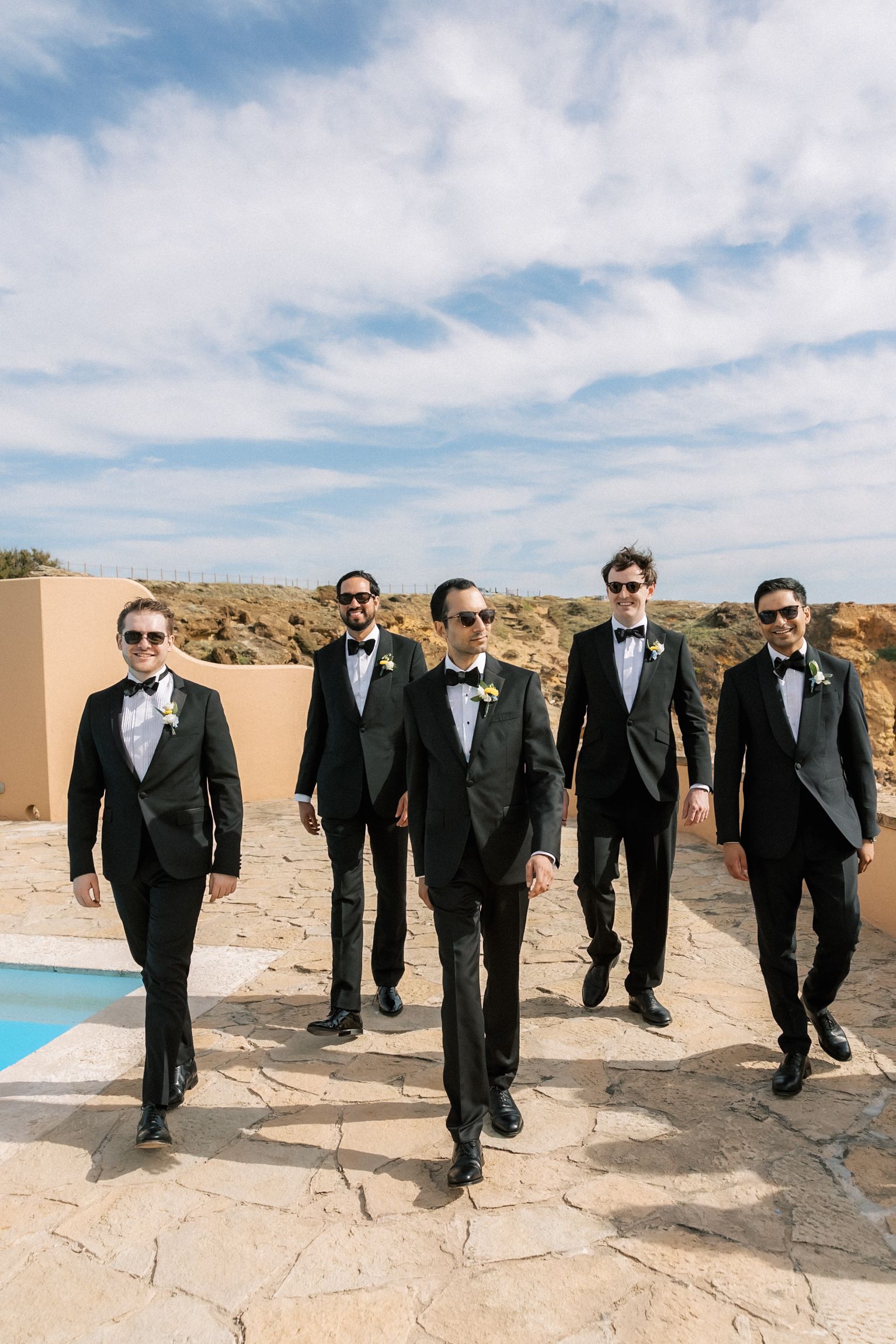 Groom sharing a relaxed moment with his groomsmen before the wedding ceremony overlooking the Atlantic Ocean.