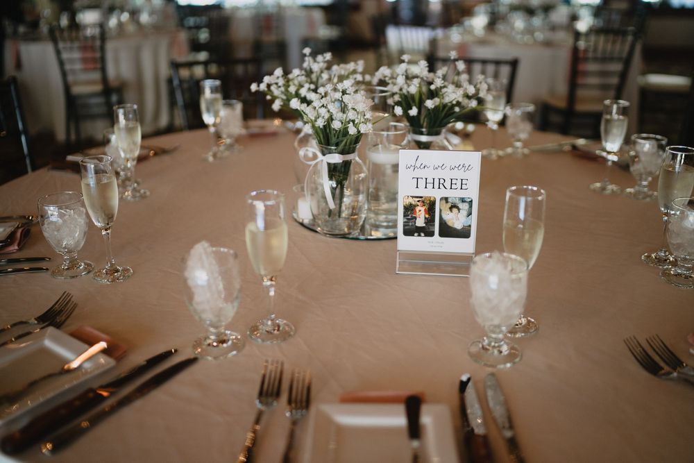 Elegant wedding reception table setting with white floral centerpiece, champagne glasses, and table number three card.
