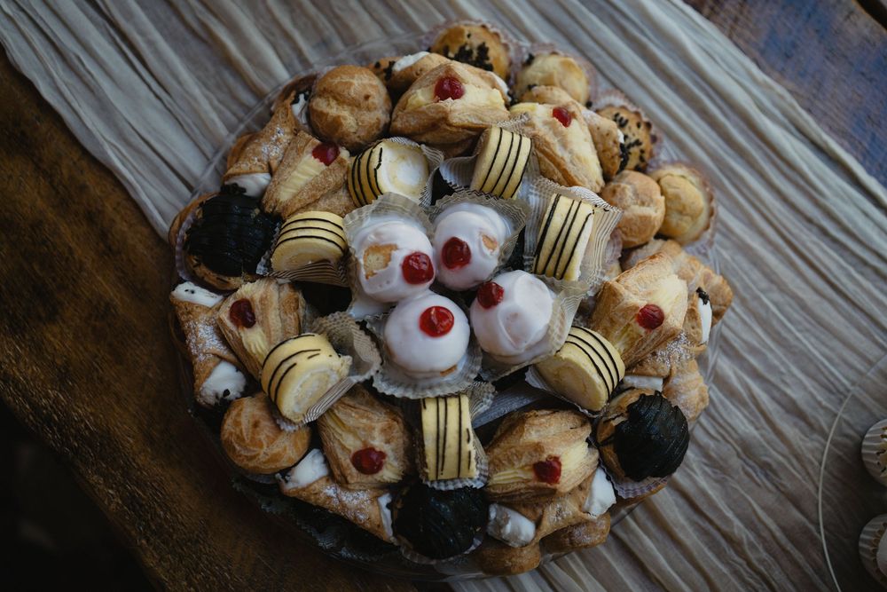 Assorted Italian pastries and cannoli arranged on a decorative plate, featuring cream-filled desserts with cherries.