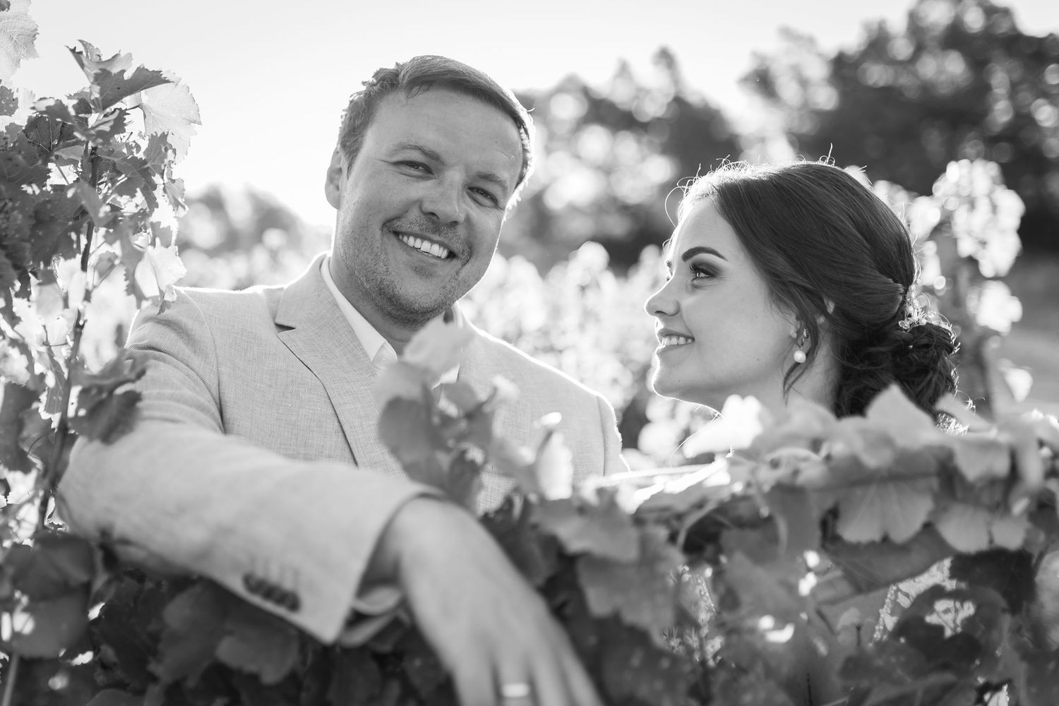 Black and white photo of a smiling couple surrounded by blooming flowers, ideal for wedding photography inspiration.