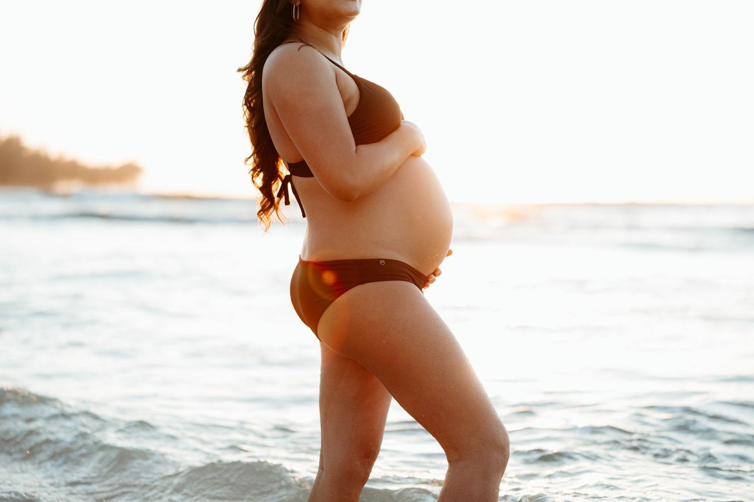 Mom-to-be celebrating pregnancy during a beach maternity session in Haena at Tunnels Beach, Kauai.