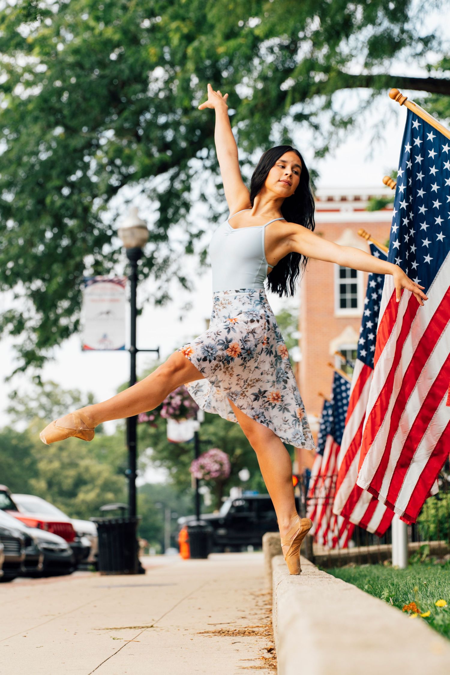 Professional dancer senior portrait photographer session, ballerina in floral skirt posed en pointe on Crown Point's Main Street.