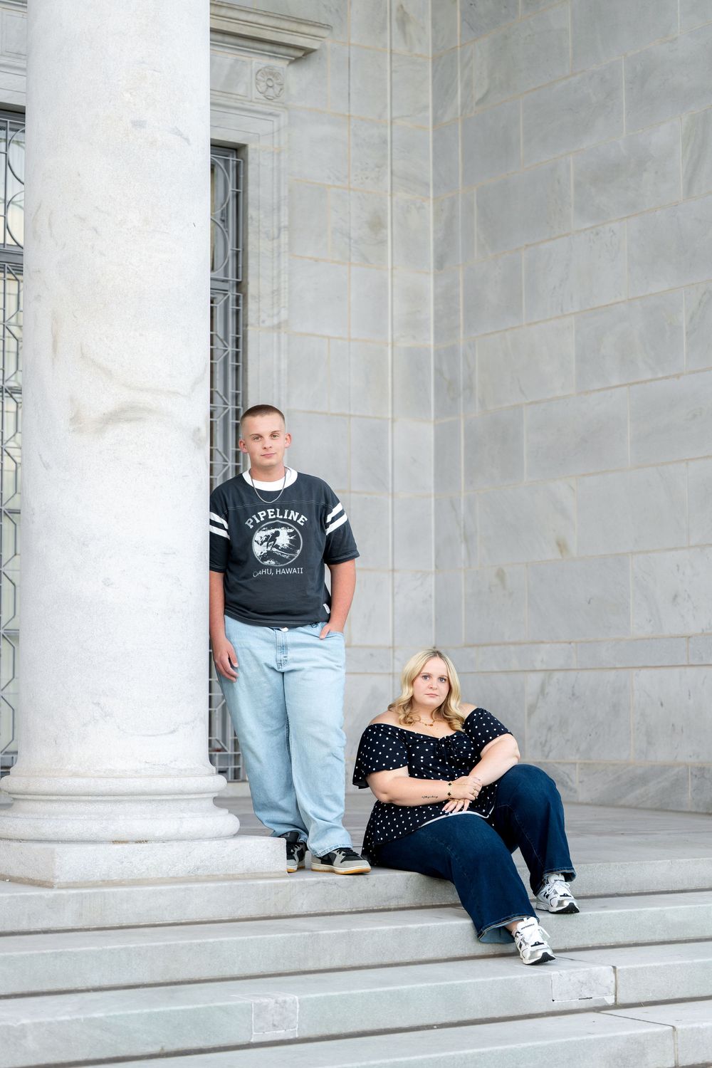 Teen boy and woman posing on marble steps with large columns at a formal building.