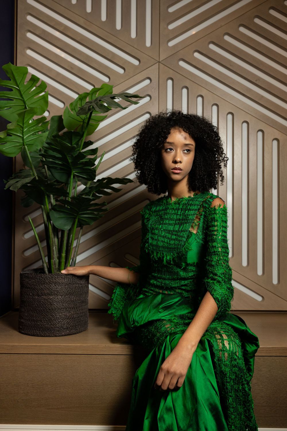 High fashion green dress with intricate details captured in studio with modern wall design.