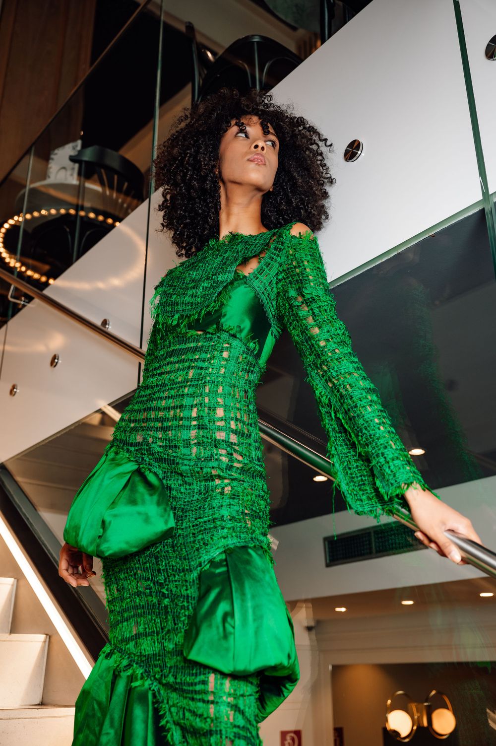 Fashion editorial featuring bright green structured dress in modern industrial space.