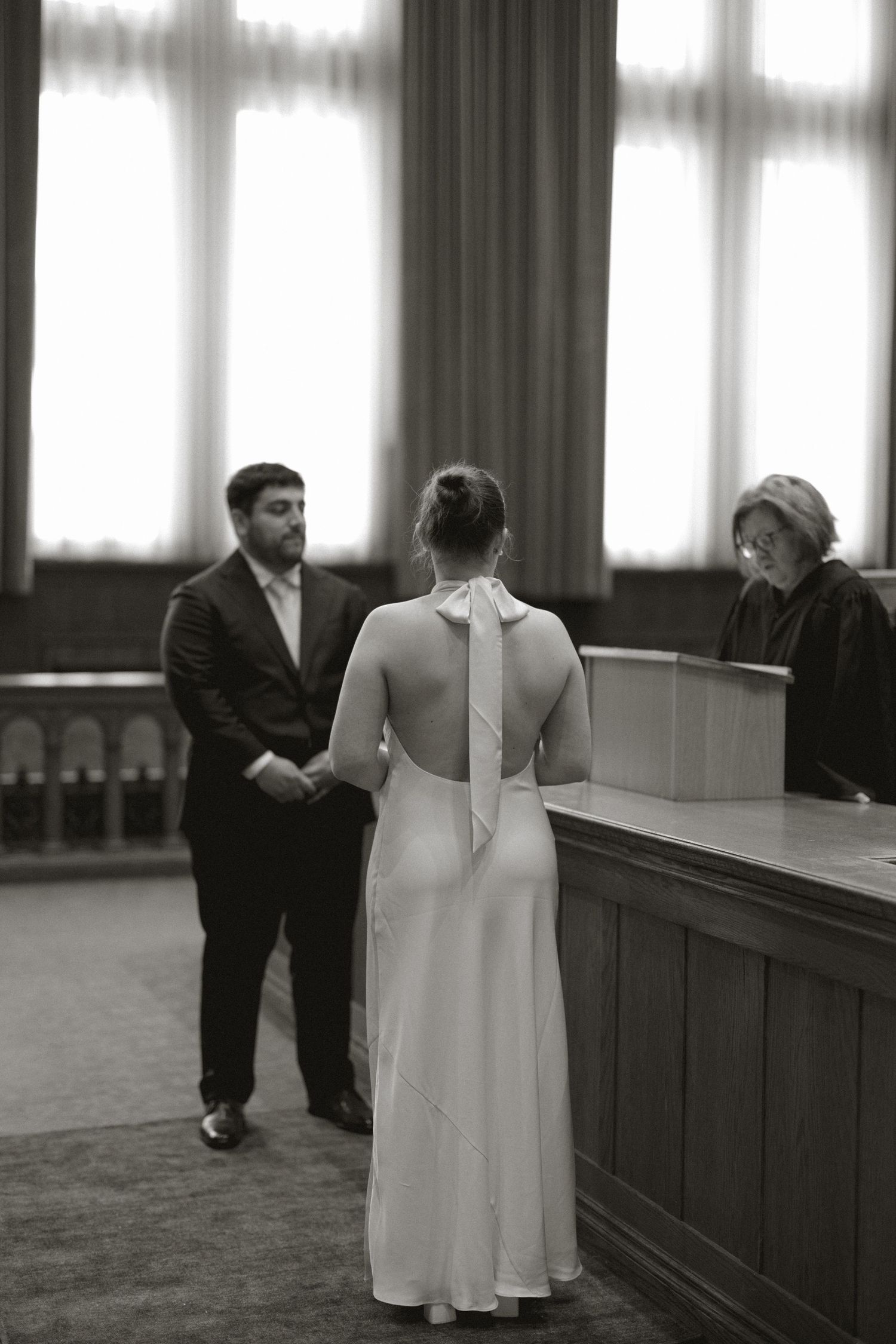 Bride and groom exchange vows before a judge at a courthouse wedding ceremony in black and white photo.