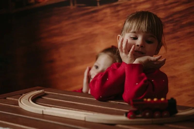 A child playing with a wooden toy train during a previous Christmas photography session.