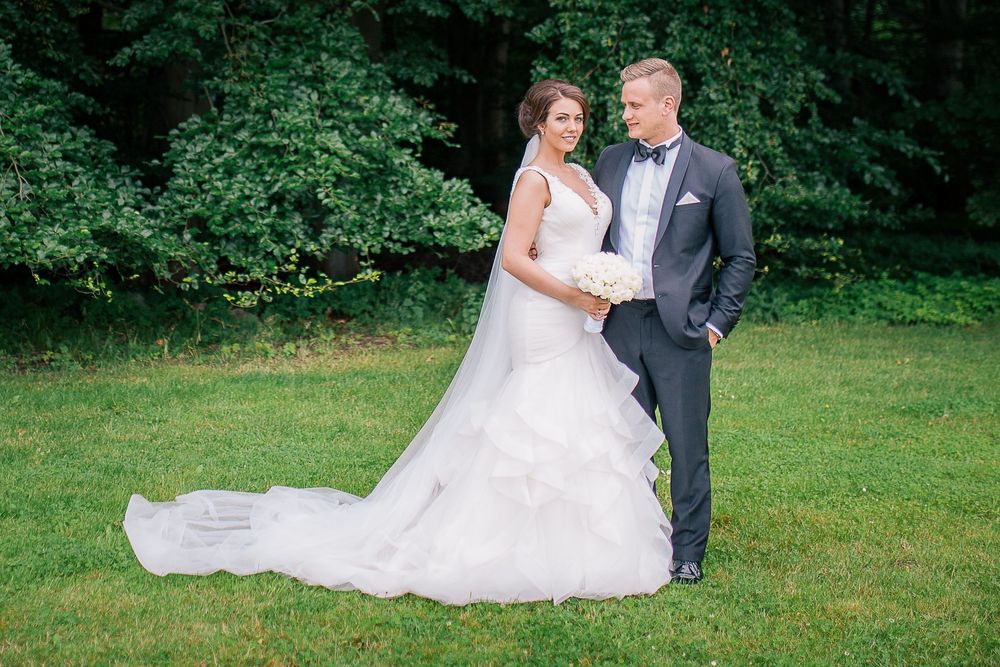 Brudepar i græs med lang brudekjole – bryllupsfoto af Martin & Louise