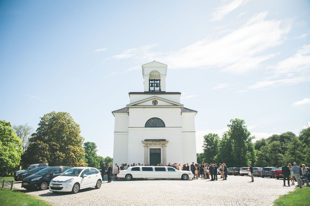 Kirke med hvid facade på en solskinsdag – bryllupsfoto af Martin & Louise