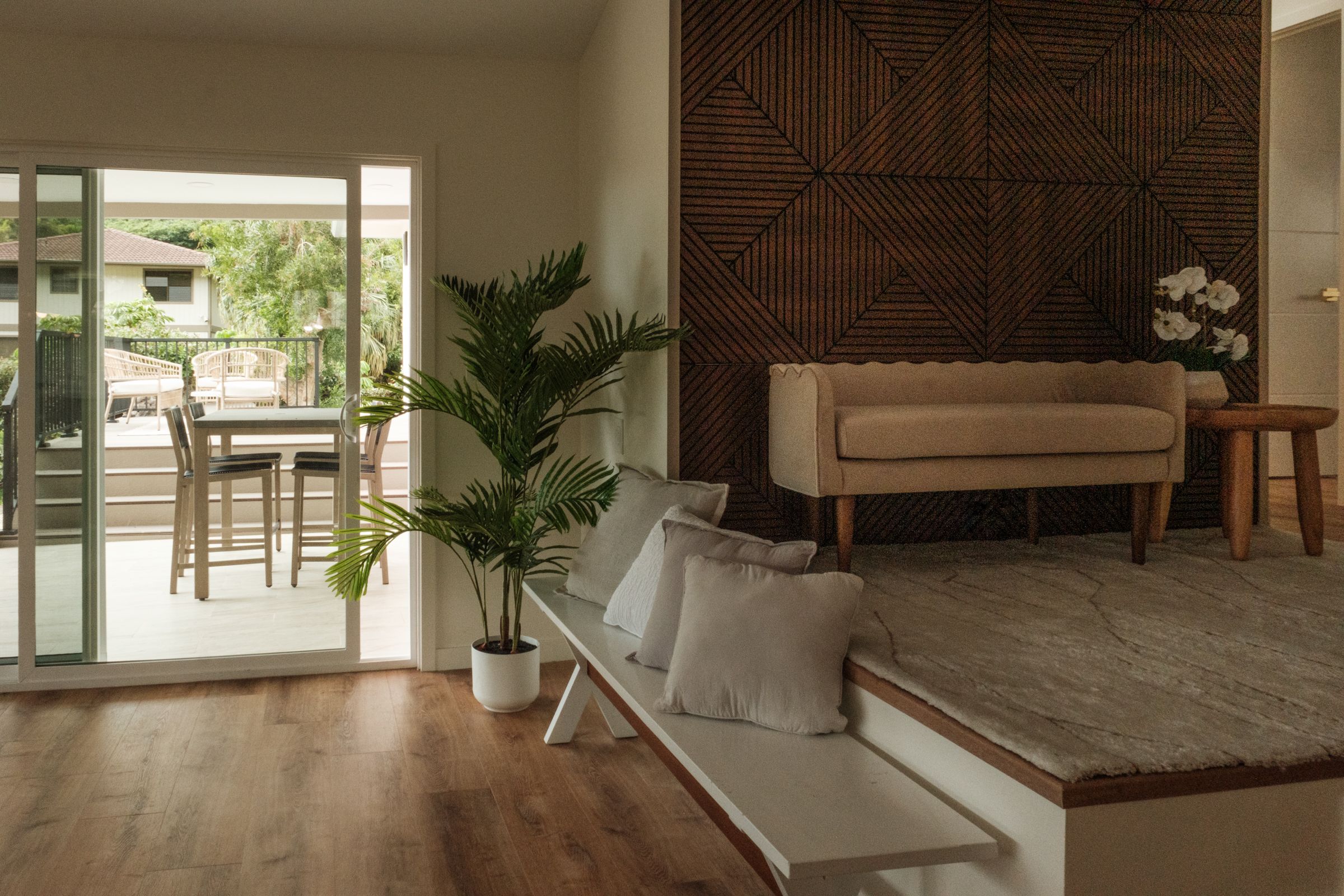 Living room with wood flooring, neutral seating, and an open doorway leading to an outdoor dining area.