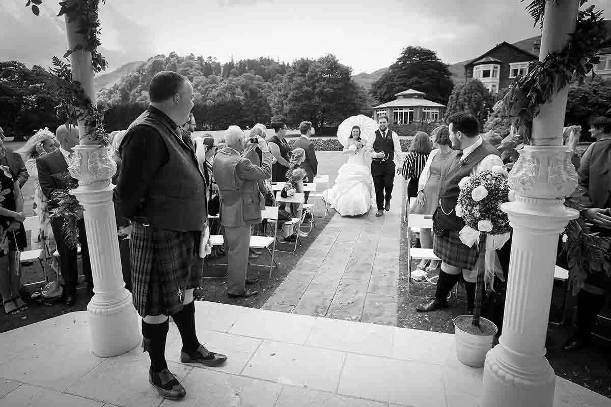 Black and white outdoor wedding ceremony with bride walking down the aisle at The Inn on the Lake