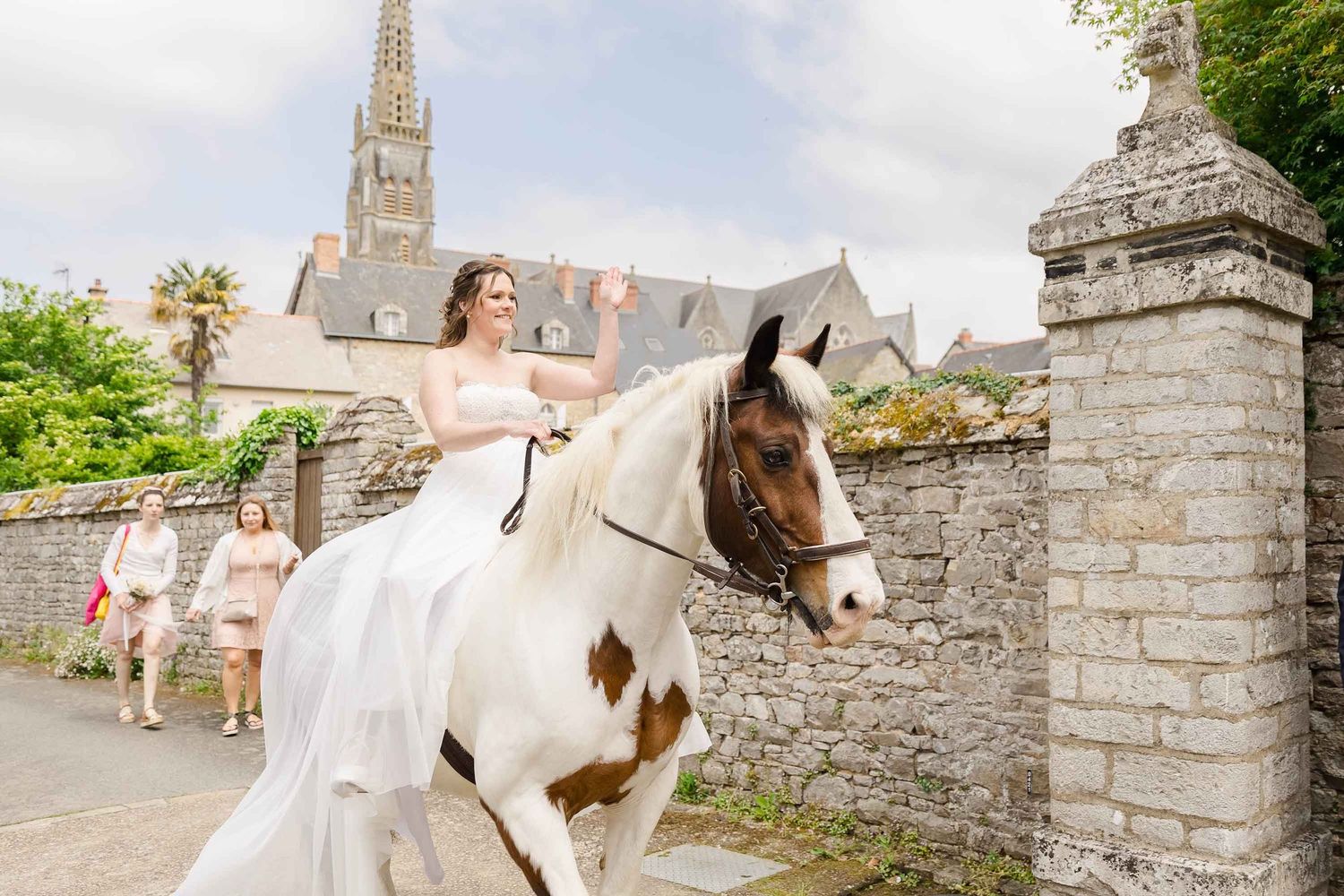 Une mariée à cheval dans les rues d'un village en Bretagne